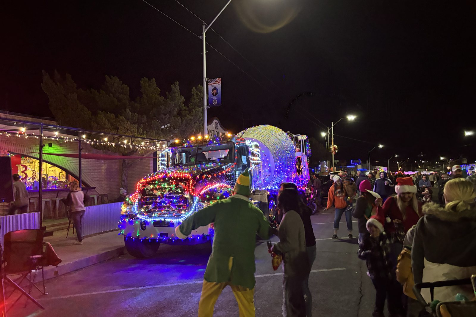 A crowd lining the street watching lit parade entries go by